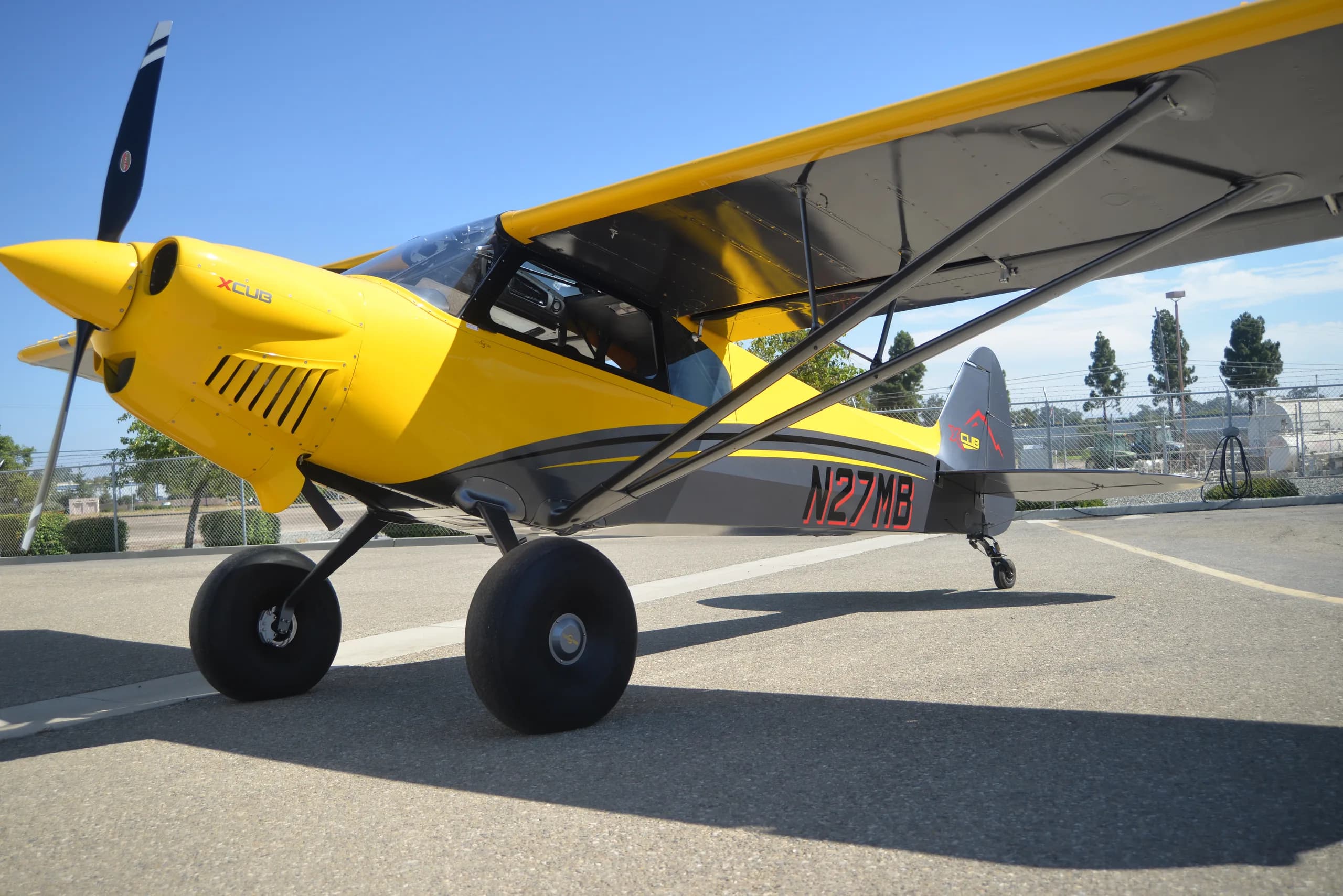 A yellow and gray CubCrafters XCub, registration N27MB, parked on the tarmac.