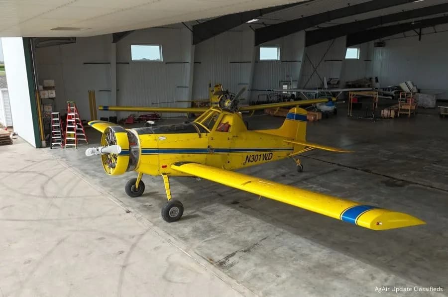 A yellow and blue Air Tractor AT-301 sits in a hangar.