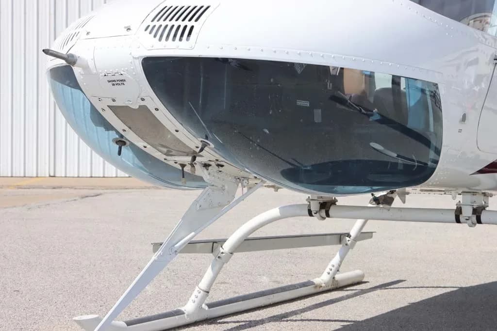 Close-up view of the front fuselage and landing skids of a white helicopter.