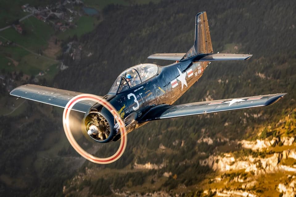 HB-RMW T-28B Trojan flying over mountains.