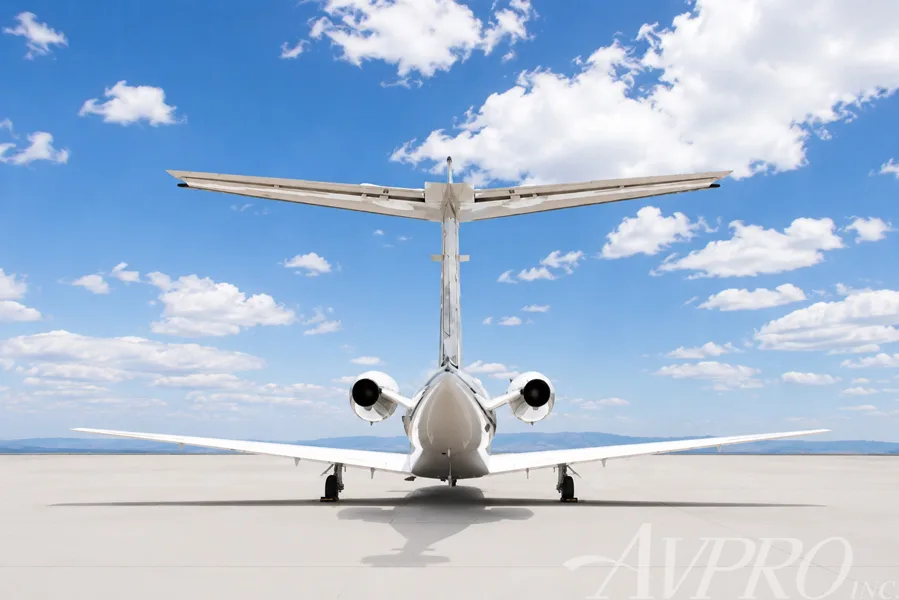 A direct rear view of a white Cessna Citation jet showing the tail, engines, and wings.