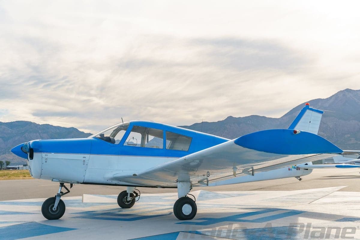 A side view of the blue and white single-engine aircraft N8718N parked on a patterned tarmac.