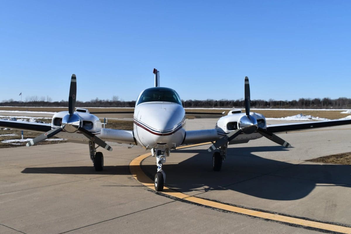 Front view of a white and red twin-engine aircraft on the tarmac.
