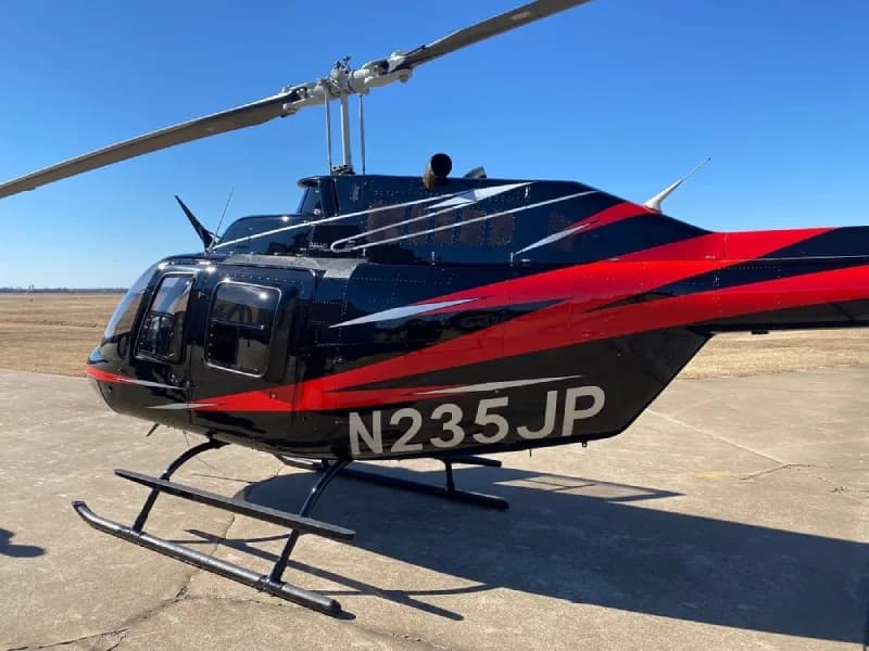 Close-up of the tail of the Bell 206L-4 helicopter, registration N235JP, showing the black and red paint scheme.