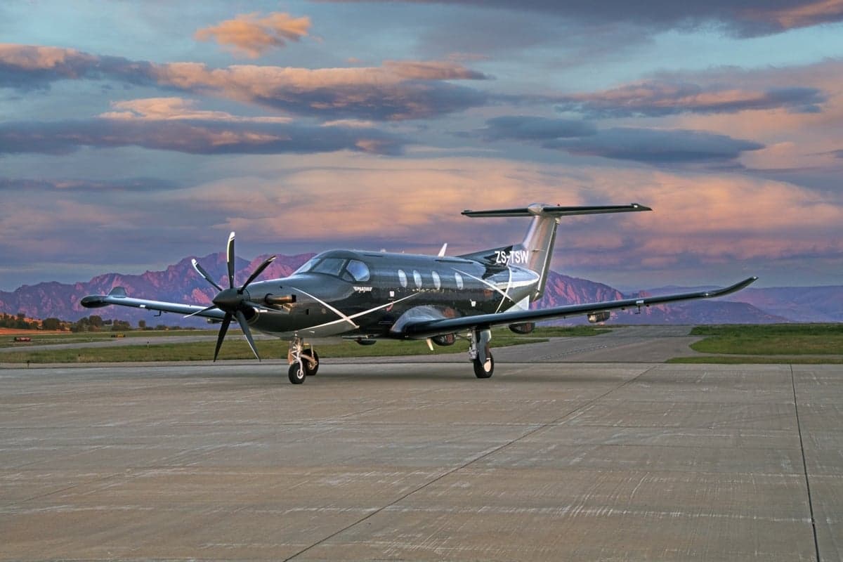 Pilatus PC-12 on the tarmac with a mountain range in the background.