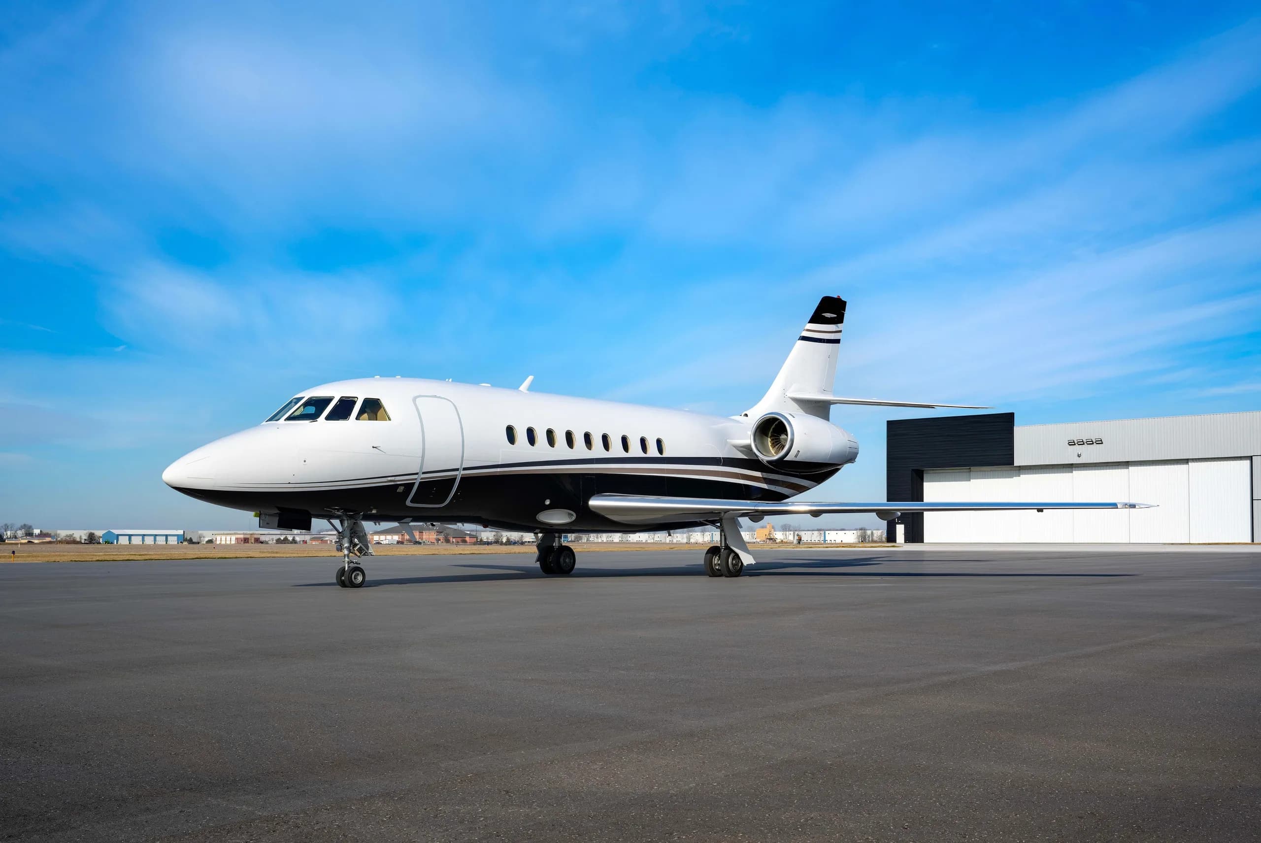 Side view of a white and black Dassault Falcon on the tarmac.