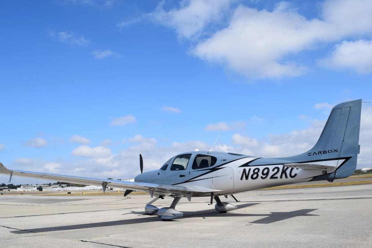 A Cirrus SR22T aircraft with a blue and silver paint scheme is parked on the tarmac.