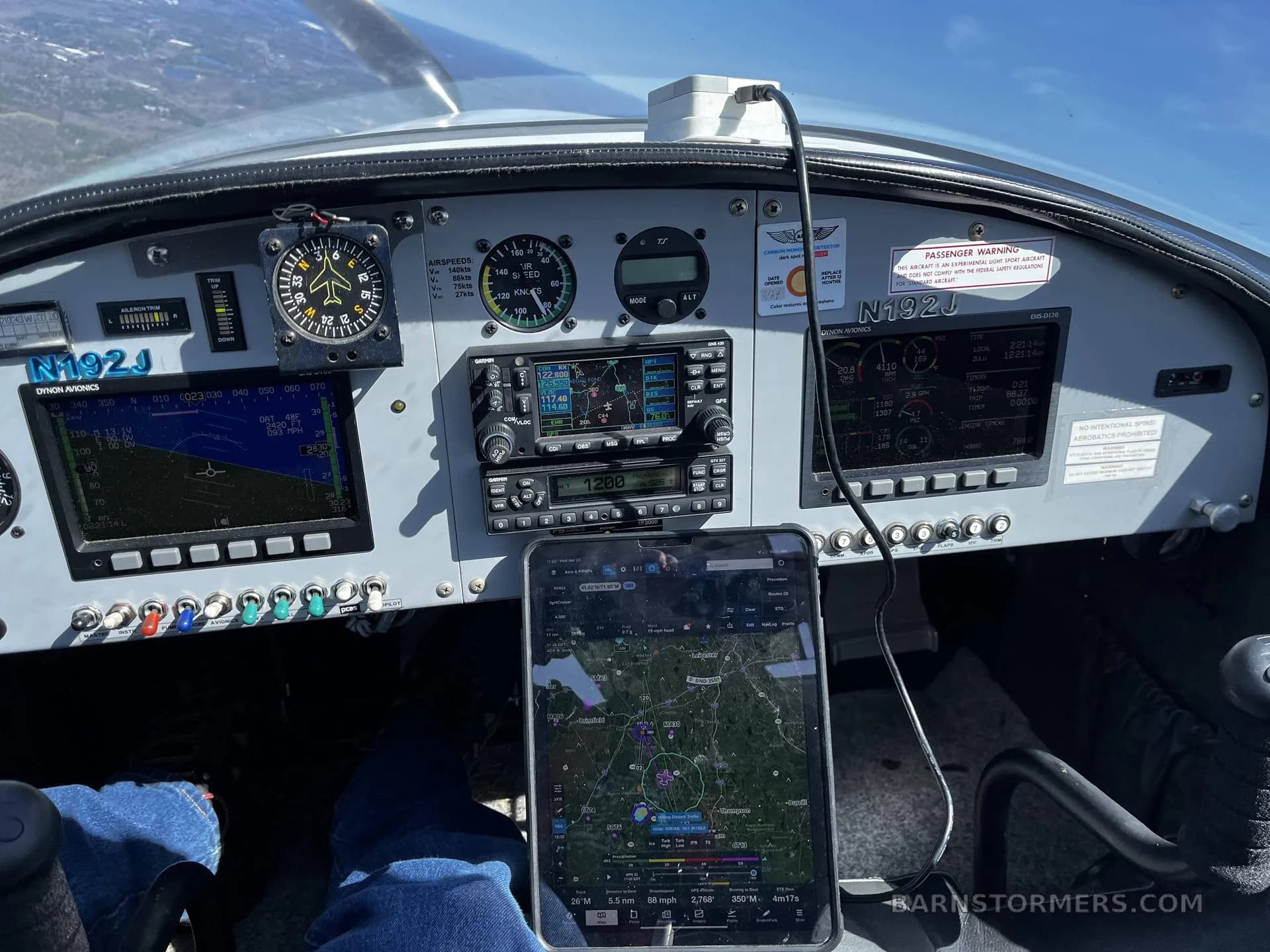 A view of an aircraft cockpit with an iPad displaying a navigation map on the pilot's lap.