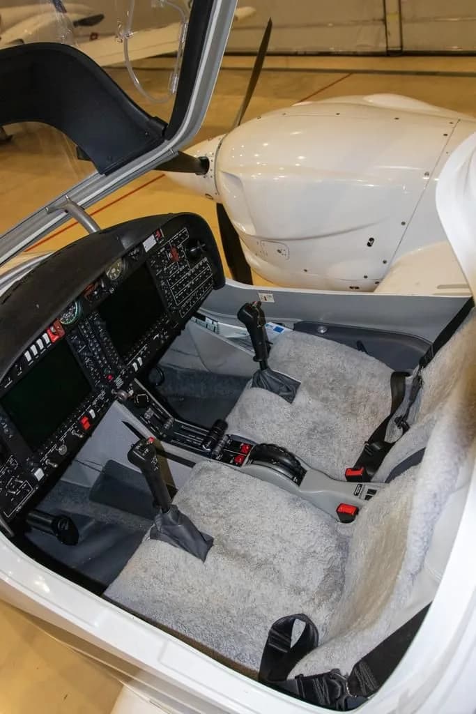 The cockpit interior of a Diamond aircraft, showing two seats with grey sheepskin covers and part of the instrument panel.