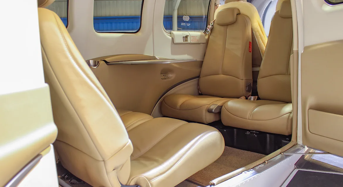 The tan leather interior cabin of a Beechcraft Baron G58, showing passenger seating.