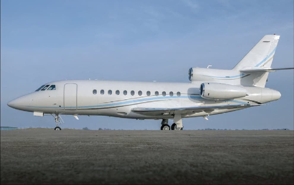 Side view of a white Falcon jet on the tarmac.