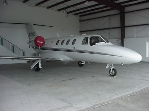A Cessna CitationJet is parked inside a hangar.