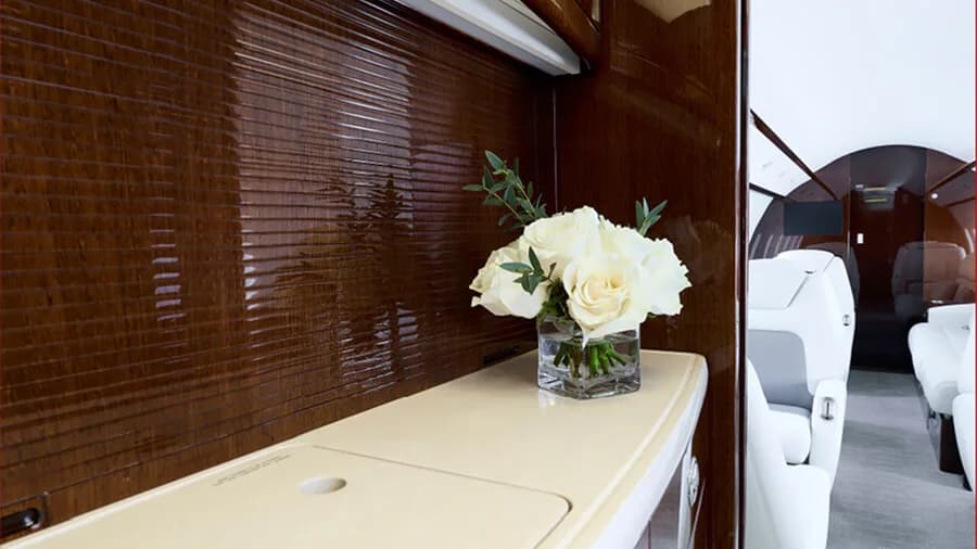 A close-up of a white flower arrangement on a counter inside the private jet cabin.