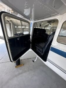 View of the open door, front seats, and cockpit of the aircraft.