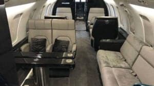 A view of the aircraft cabin showing seats, a table, and a divan.