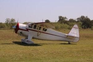 A Howard DGA-15P aircraft is parked on a grassy field.