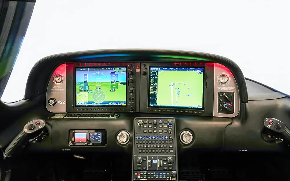 The modern glass cockpit of a Cirrus SR22 aircraft, featuring two large display screens and a central control panel.