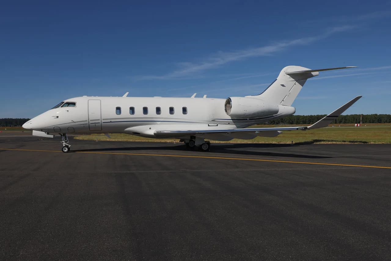 Side view of a white private jet with blue accents on the tarmac.