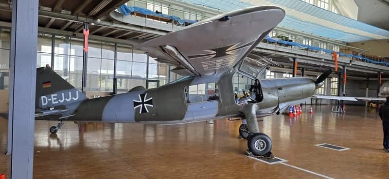 Side view of a gray and green aircraft with German markings in a hangar.