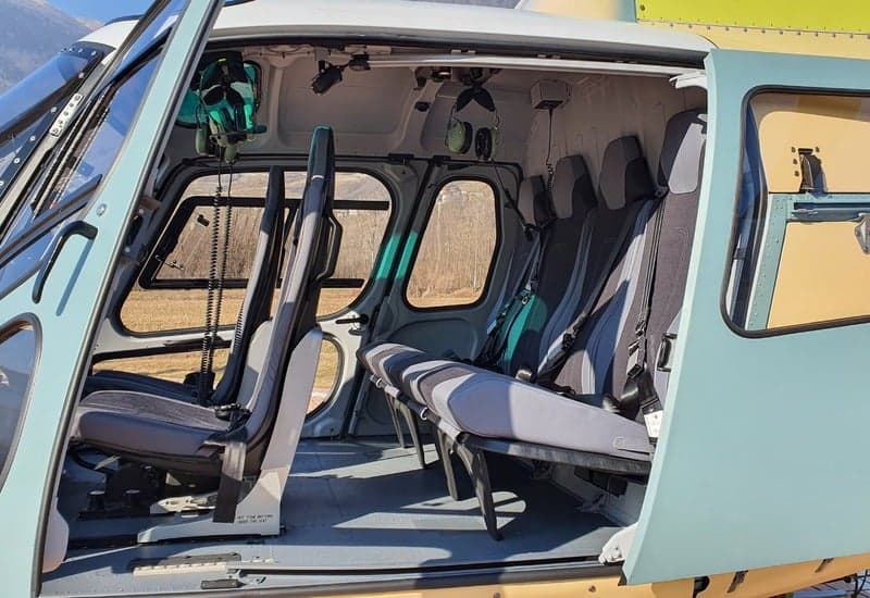 The interior of a helicopter with gray seats and an open door.