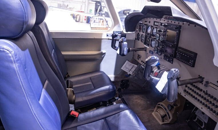 View of the aircraft cabin with blue leather seats and cockpit in the background.