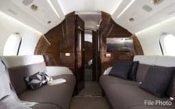 Interior of the Falcon jet with comfortable seating and wood paneling.