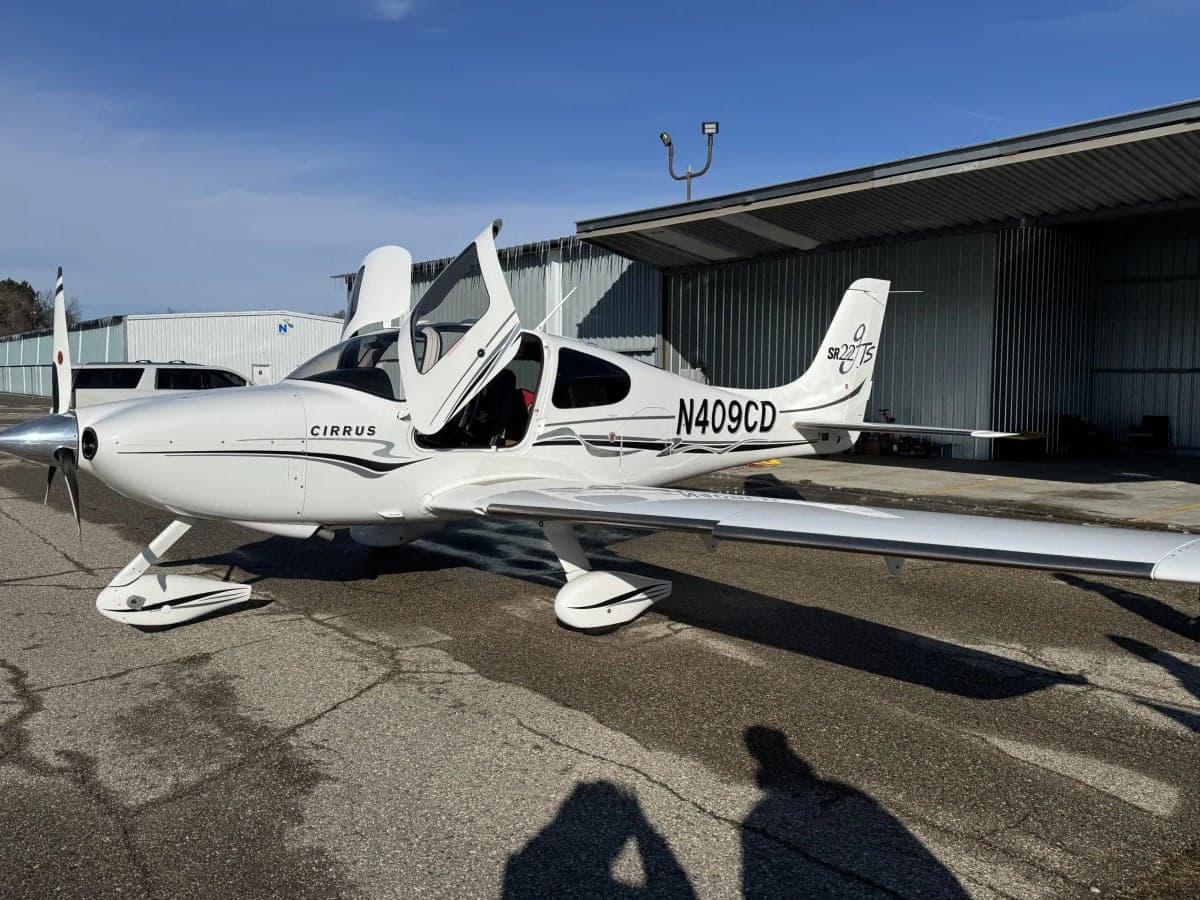 Full side view of a Cirrus SR22T with open doors, parked on the tarmac.