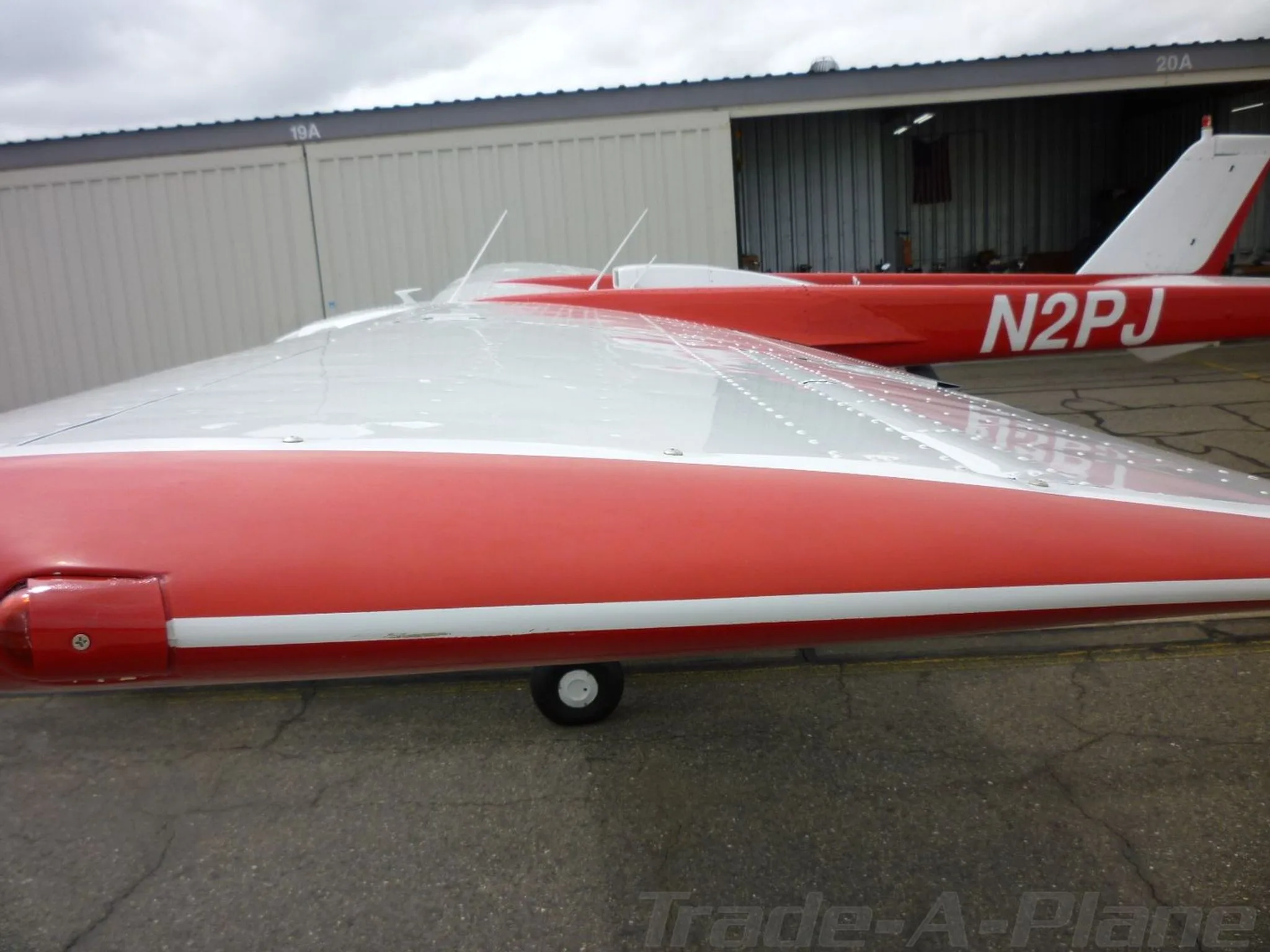 A close-up of the red and white wing and fuselage of the Cessna Skymaster N2PJ, showing rivets and antennas.