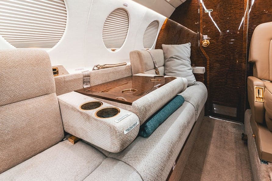 A comfortable couch with a side table is featured in the Falcon 7X cabin.