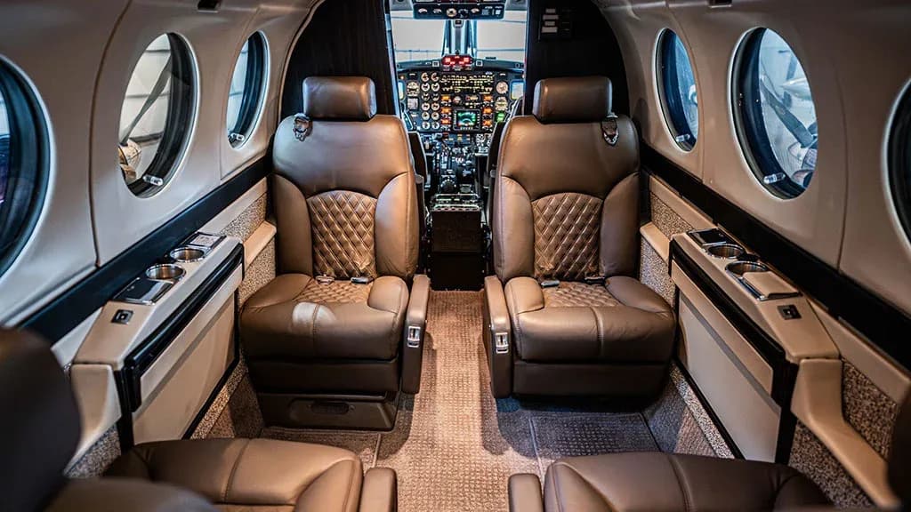 The aircraft's interior cabin with brown quilted leather seats and a clear view of the cockpit instruments.