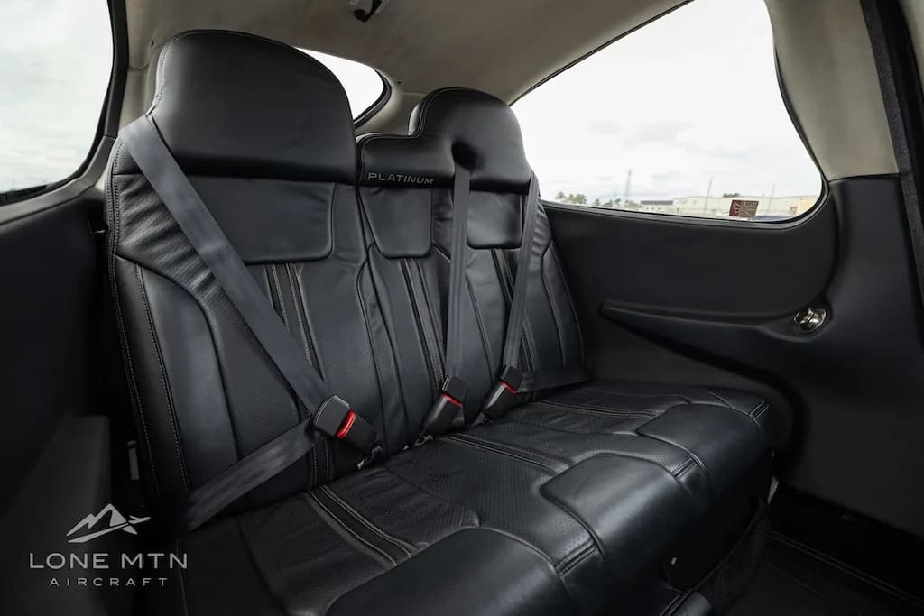Angled view of the black leather rear seats inside the aircraft cabin.