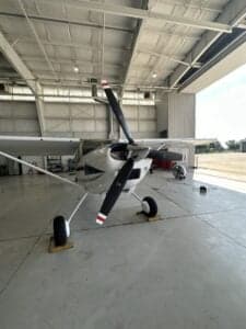 Front view of a Cessna aircraft with a white and blue paint scheme parked in a hangar.