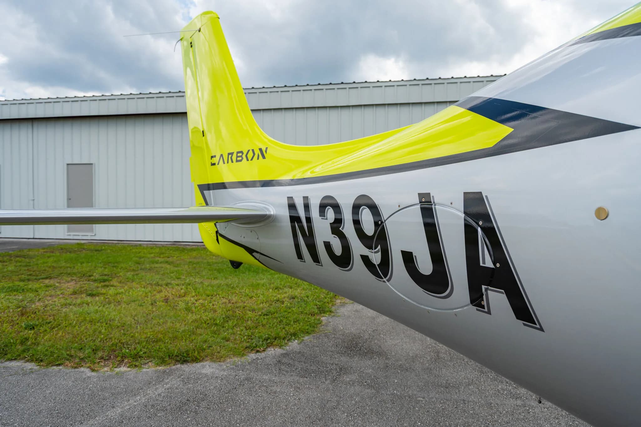 Close-up of the tail section of a lime green and silver Cirrus SR20 aircraft, showing the registration N39JA and "CARBON" decal.
