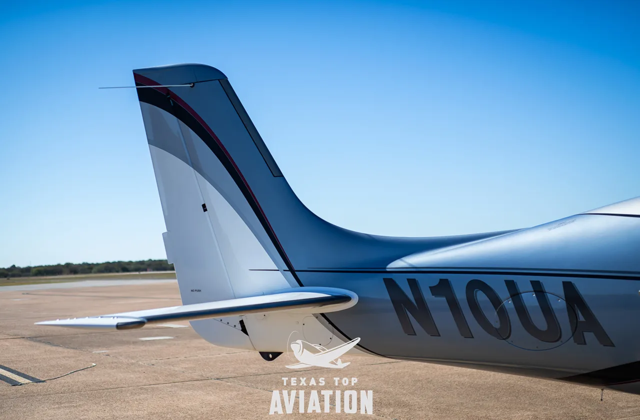 Close-up of the tail and rear fuselage of a silver and white Cirrus SR22 aircraft (N10UA).