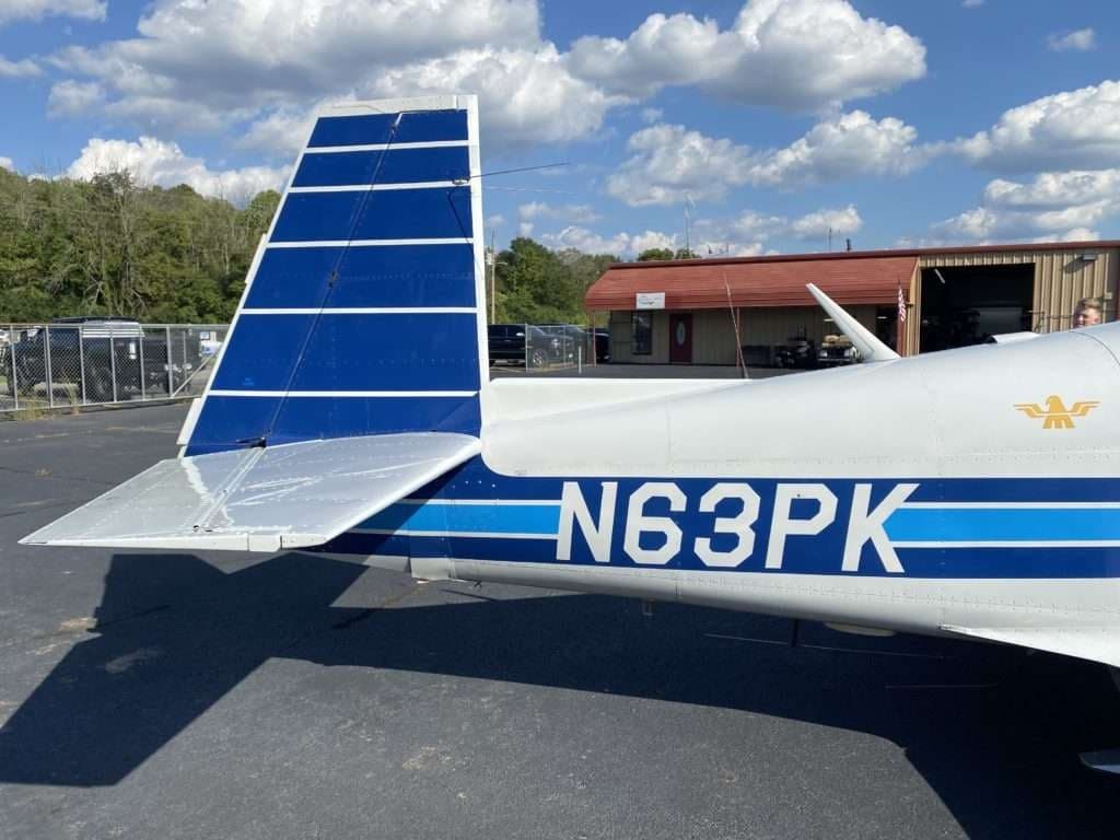 Close-up of the tail section of the Mooney M20C aircraft, showing the tail number N63PK.