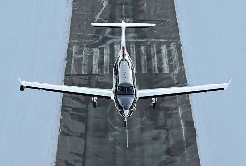 Pilatus PC-12 flying over a runway.