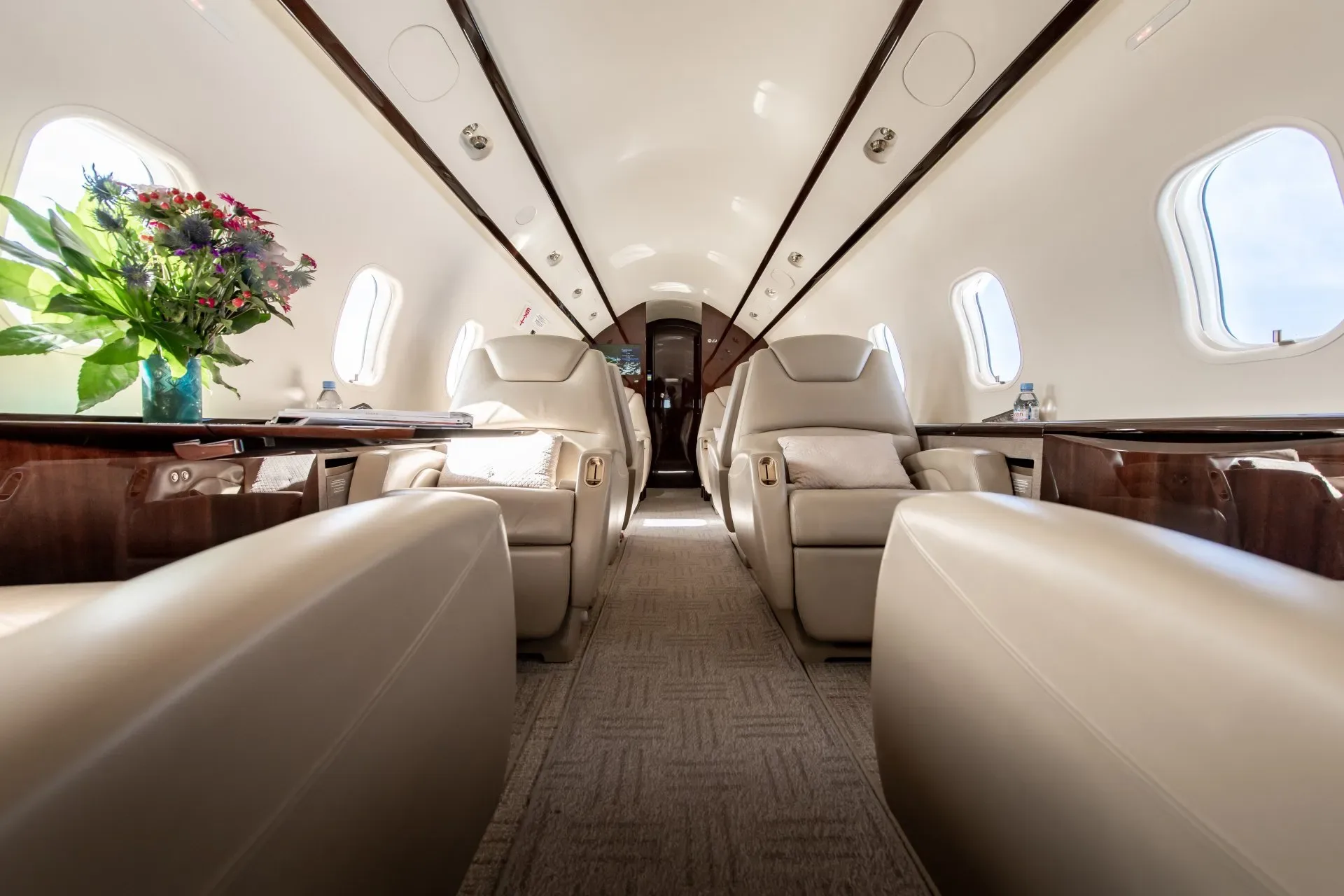 A view down the aisle of the aircraft's interior with leather seats and tables.