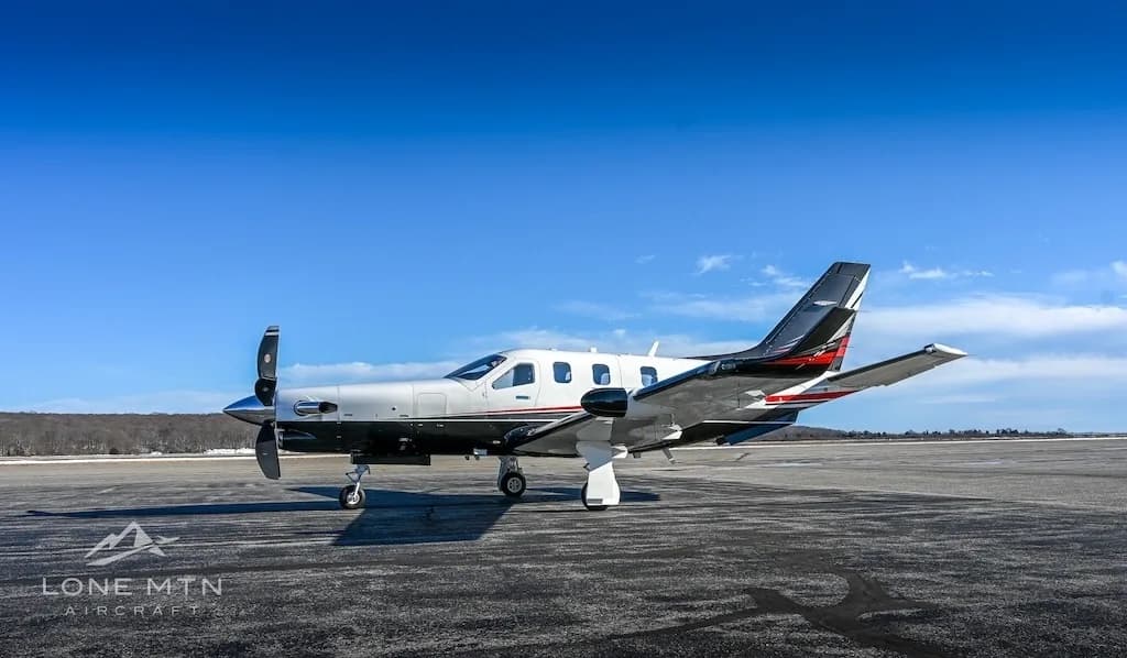 A TBM 940 aircraft, registration N944EA, parked on a runway or large tarmac under a clear blue sky.