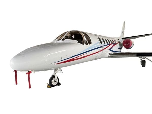 A white Cessna Citation business jet with red and blue stripes, seen from the front-left, with "N194SA" on the tail.
