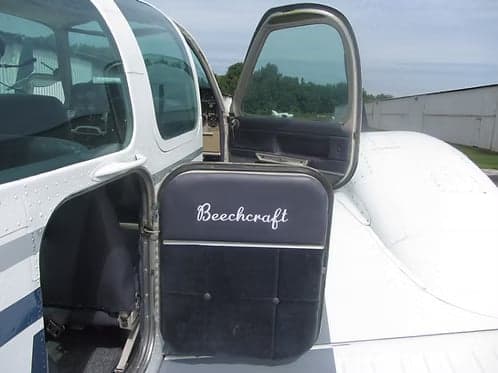Open door of a Beechcraft Bonanza with the Beechcraft logo on the door panel.