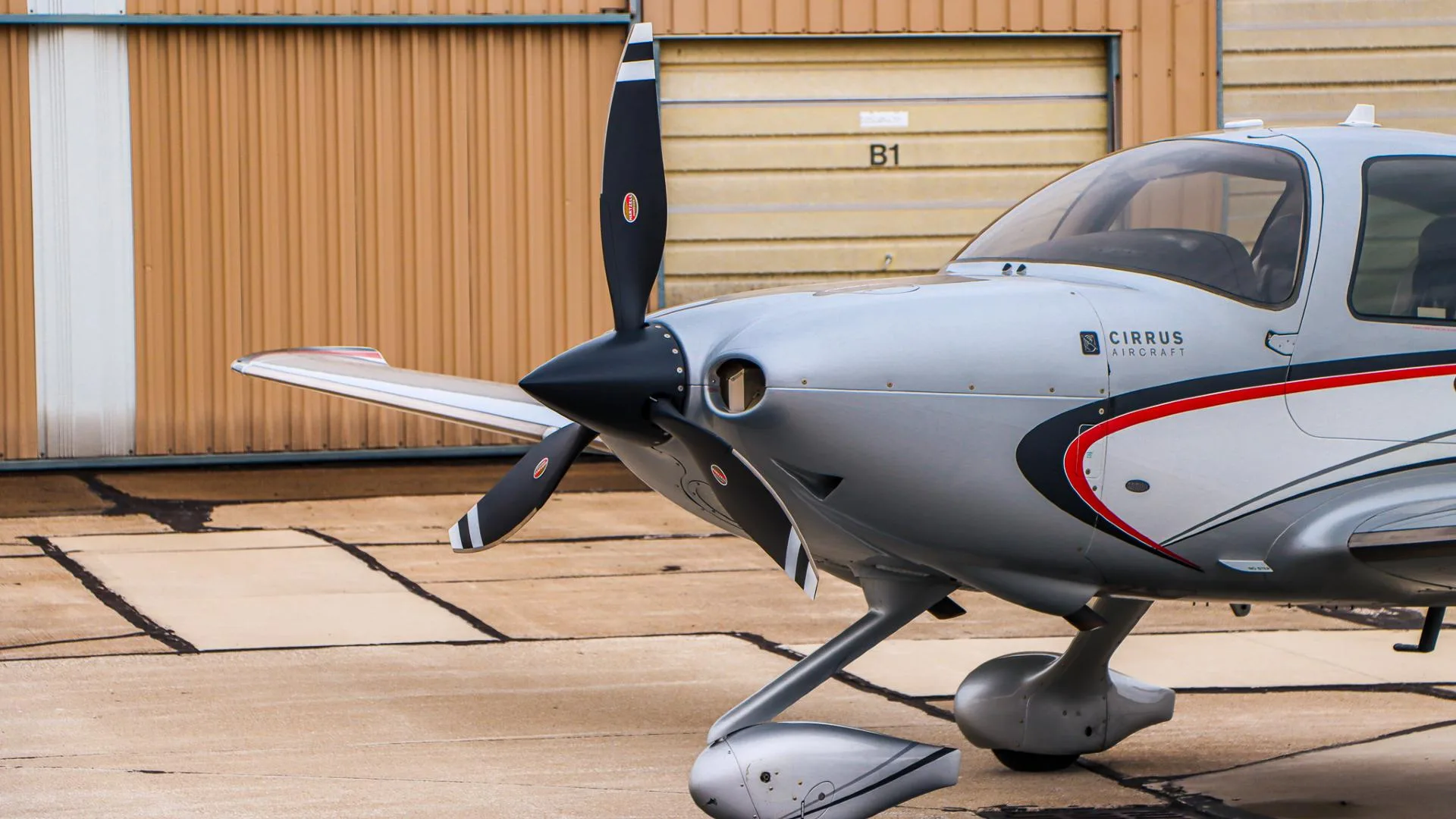 A close-up of the front-left fuselage and propeller of the Cirrus SR22 N553MC, showing 'CIRRUS AIRCRAFT' text.