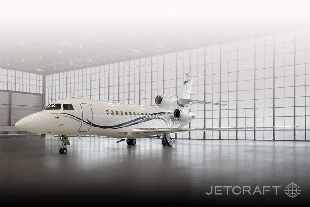 A Falcon aircraft is parked inside a hangar with large windows.