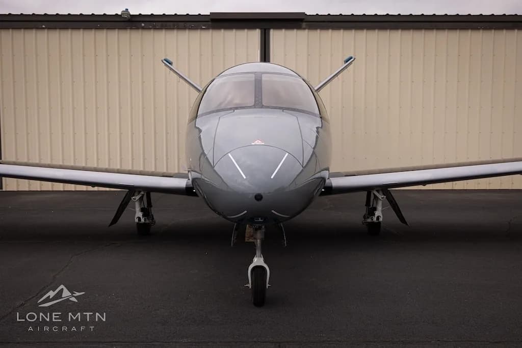 A head-on view of the grey Cirrus Vision Jet parked on an airfield.