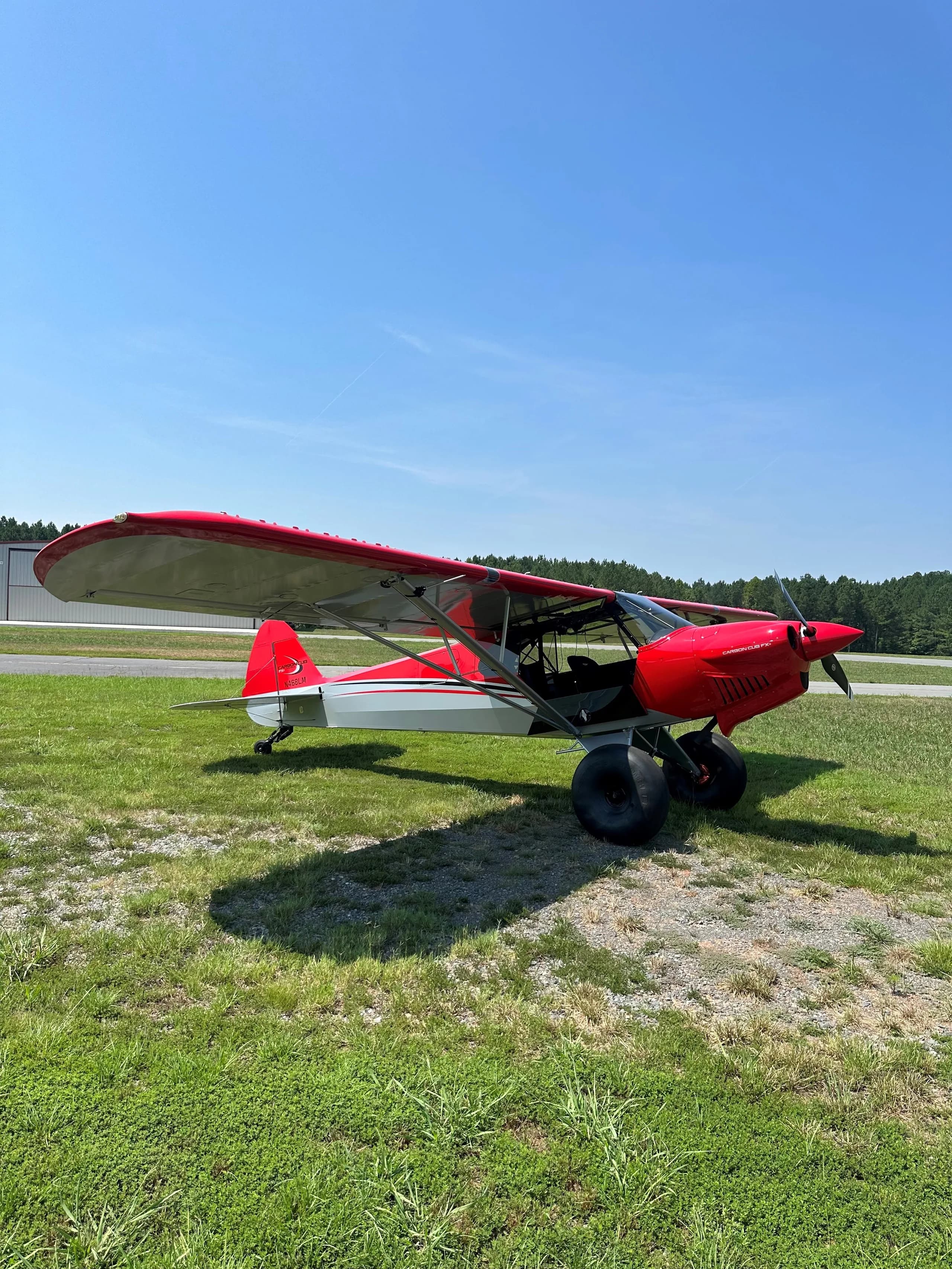 A red and silver Carbon Cub FX-3 on a grassy field.