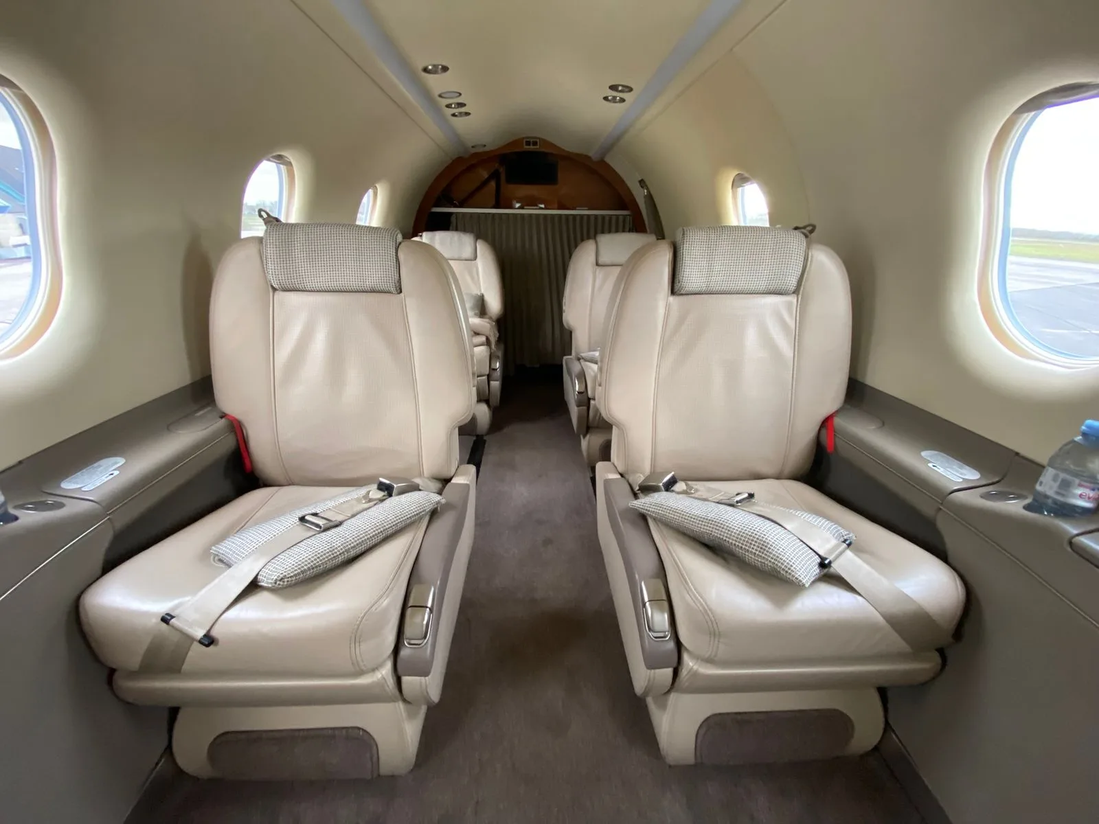 The interior cabin of a Pilatus PC-12 NG, showing two rows of beige leather seats facing each other.