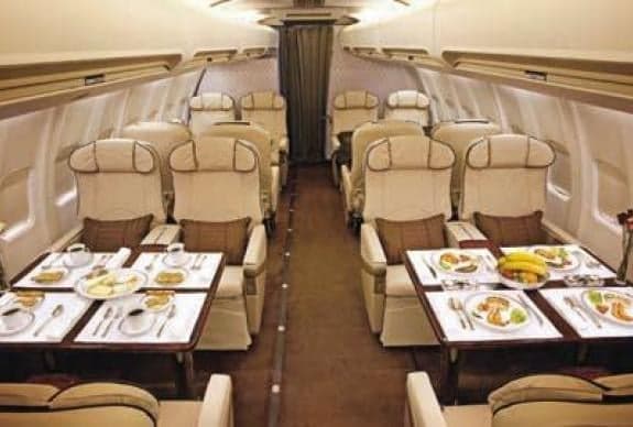 Interior of a private jet with dining tables set for a meal.
