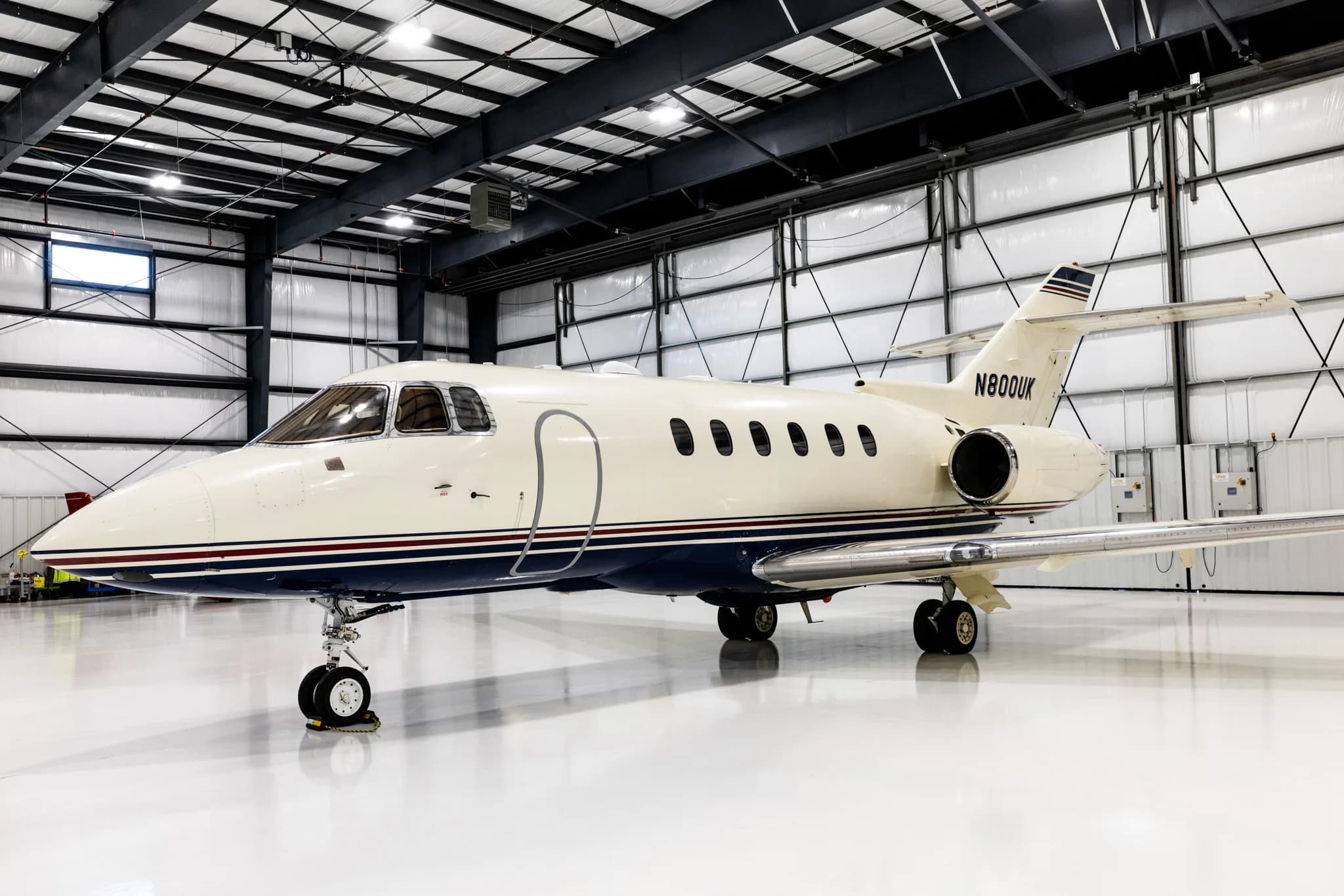 A side view of the N800UK business jet parked inside a brightly lit hangar.