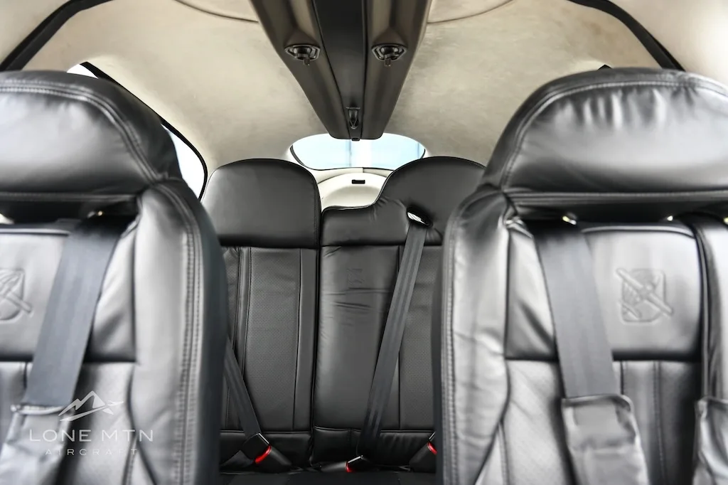View from the front seats looking back at the black leather rear seats of a Cirrus SR22 aircraft.