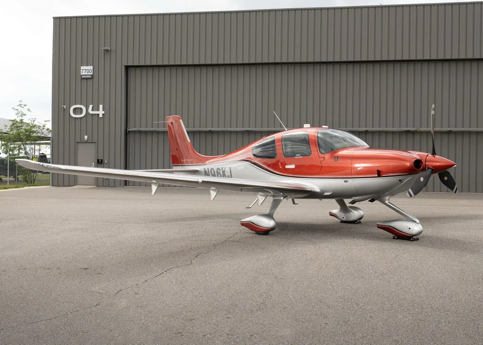 A three-quarter front view of a red and silver Cirrus SR22T aircraft, registration N96KJ, parked on an asphalt apron.