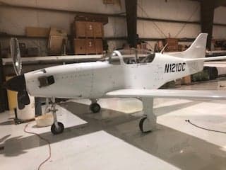 A white aircraft with tail number N121DC is parked in a hangar.